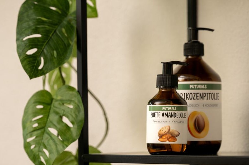 Biologische massageoliën – zoete amandelolie en abrikozenpittolie – op een plank