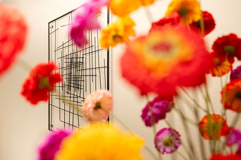 Kleurrijke bloemen voor een zwart metalen wandkunstwerk in het massage-atelier